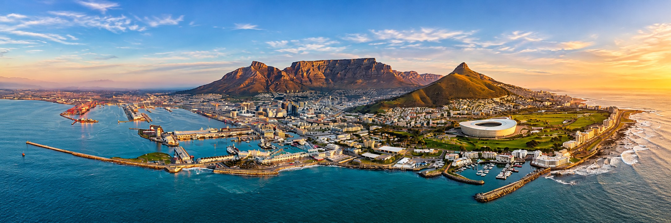 Panoramic view of Cape Town at golden hour, with Table Mountain, Lion's Head, the city and the V&A Waterfront